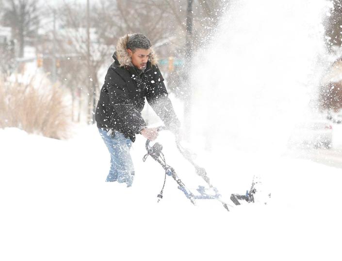 Jalen Podsiadlo uses a snow blower Monday to clear his driveway in the Firestone Park neighborhood of Akron.