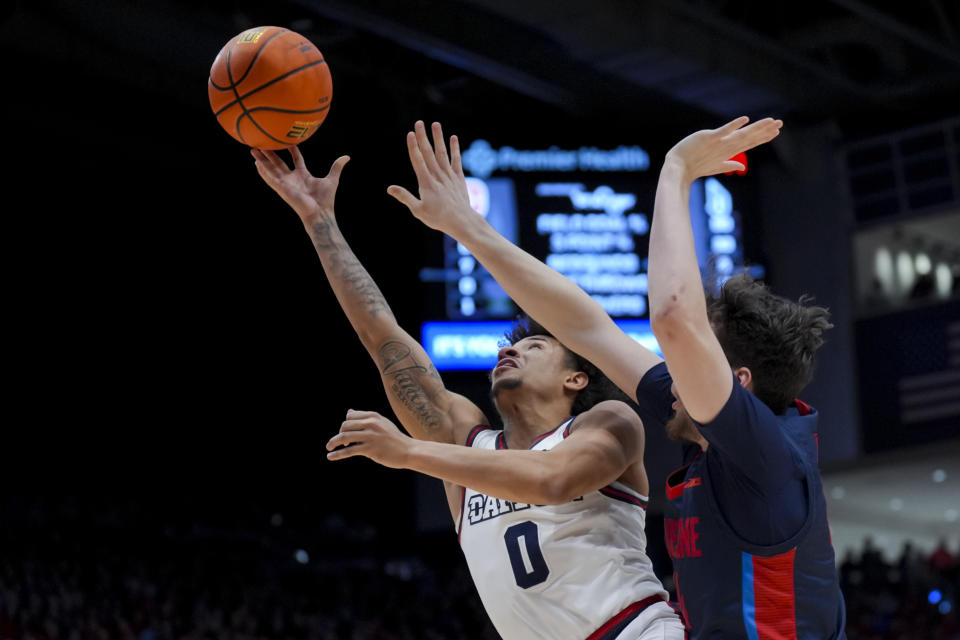 Dayton guard Javon Bennett, left, drives to the basket as he is fouled by Duquesne guard Jake DiMichele during the first half of an NCAA college basketball game, Tuesday, Feb. 13, 2024, in Dayton, Ohio. (AP Photo/Aaron Doster)