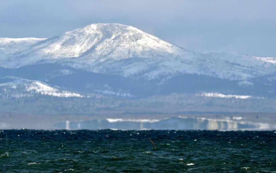 Kunashiri Island, one of four southern Kuril islands, which Japan calls the Northern Territories, is seen from the Notsuke Peninsula in Betsukai in Japan's northernmost major island of Hokkaido Thursday, Dec. 15, 2016. Russian President Vladimir Putin arrived in Japan on Thursday for a two-day summit that marks his first official visit to a G-7 country since Russia's 2014 annexation of Crimea. During two days of talks, Japan's Prime Minister Shinzo Abe hopes to make progress on a long-running territorial dispute over the four islands, while trying to bolster ties with economic projects. Japanese on the board reads: "Kunashiri, the island close but far." (Yoshiaki Sakamoto/Kyodo News via AP)