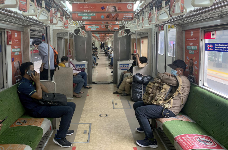 FILE - Passengers wearing protective face masks as they sit in social distancing inside a train leaving a train station in Jakarta, Indonesia on Dec. 16, 2021. Indonesia, where Sinovac has been the mainstay of a campaign to vaccinate its 270 million residents, is offering a Moderna booster for health care workers. The government is also planning boosters for the general population in January, though it hasn’t said which vaccine. (AP Photo/Tatan Syuflana, File)