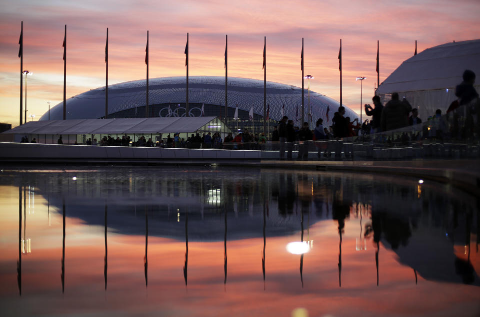 The sun sets as the Bolshoy Ice Dome is reflected in a pool of water underneath the Olympic cauldron at the 2014 Winter Olympics, Thursday, Feb. 13, 2014, in Sochi, Russia. 