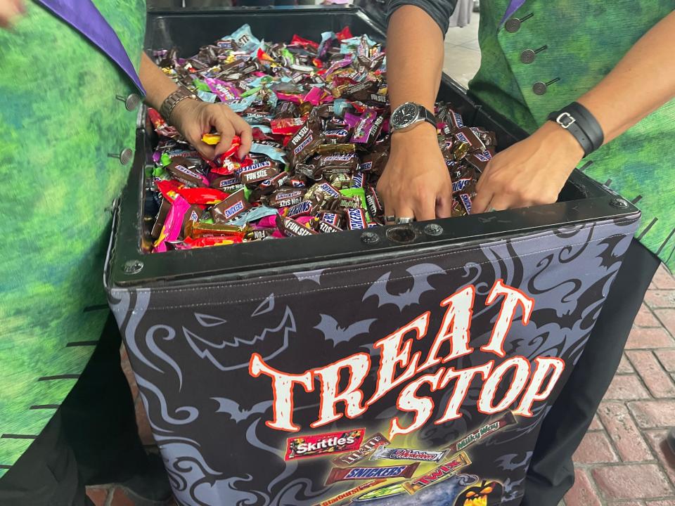 hands reaching into a barrel of candy on a trick or treat trail at oogie boogie bash