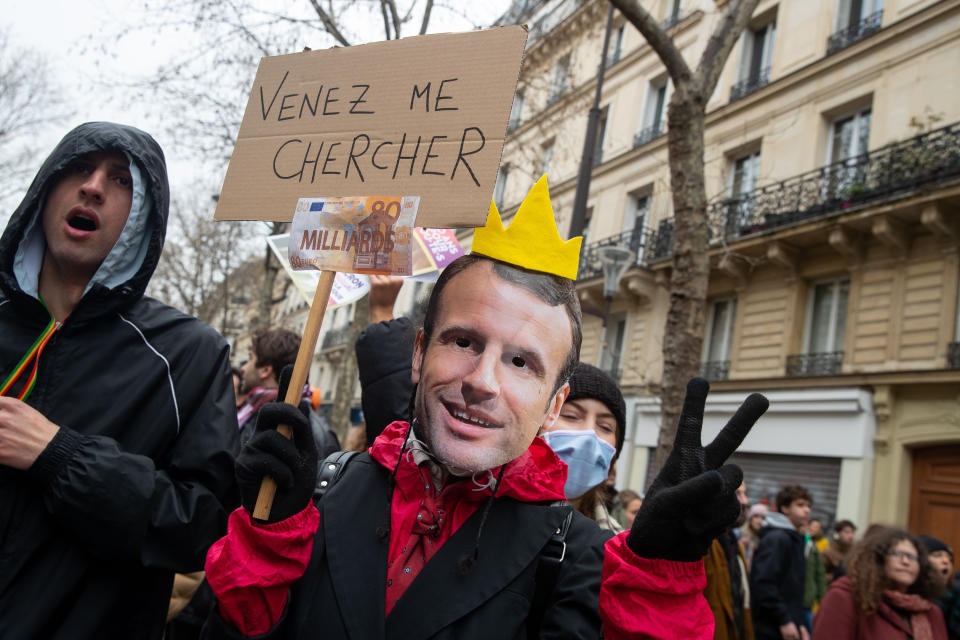 A protester wearing a mask with President Macron's face