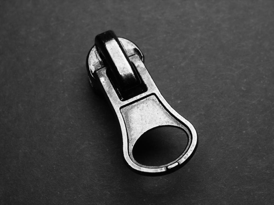 Metallic zipper pull on grey background 