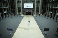 A man walks in the empty atrium, usually full of tables for journalists to work during EU summits, at the European Council building in Brussels, Thursday, July 16, 2020. On Friday, July 17, 2020, leaders from the 27 European Union nations will meet face-to-face to try to carve up a potential package of 1.85 trillion euros among themselves. Due to coronavirus concerns, Friday's summit will be held in a larger-than-usual meeting room to meet social distancing requirements, the media will be kept to a minimum and there will be no group photo of the leaders. (AP Photo/Francisco Seco)