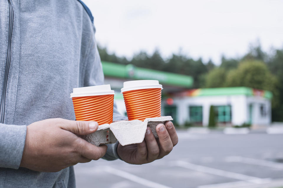 Someone holding two cups of coffee on a drink carrier