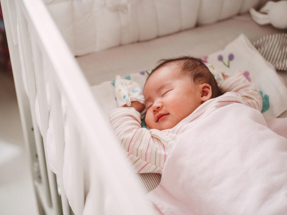 adorable new born baby smiling sweetly while sleeping soundly in the crib