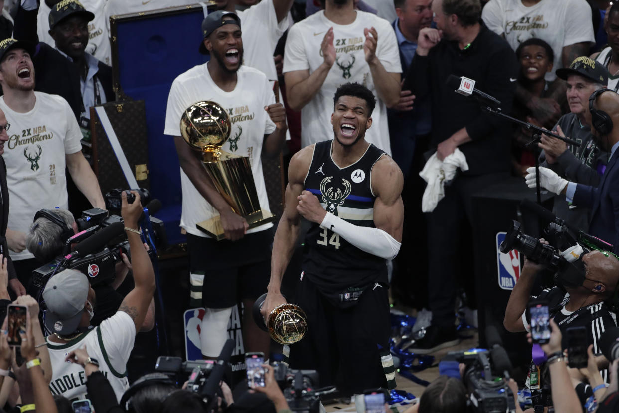 Milwaukee Bucks forward Giannis Antetokounmpo celebrates with the MVP trophy, as teammates hold the championship trophy, after defeating the Phoenix Suns in Game 6 of basketball's NBA Finals Tuesday, July 20, 2021, in Milwaukee. (AP Photo/Aaron Gash)