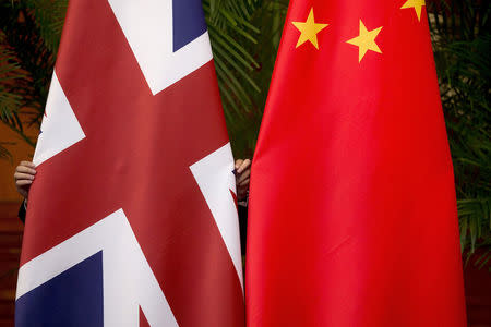 FILE PHOTO: A worker adjusts British and China (R) national flags on display for a signing ceremony at the seventh UK-China Economic and Financial Dialogue "Roundtable on Public-Private Partnerships" at Diaoyutai State Guesthouse in Beijing, China September 21, 2015. REUTERS/Andy Wong/Pool/File Photo