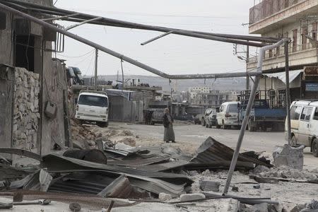 A man walks near damage in Kafr Hamra village, northern Aleppo countryside, Syria February 27, 2016. REUTERS/Abdalrhman Ismail