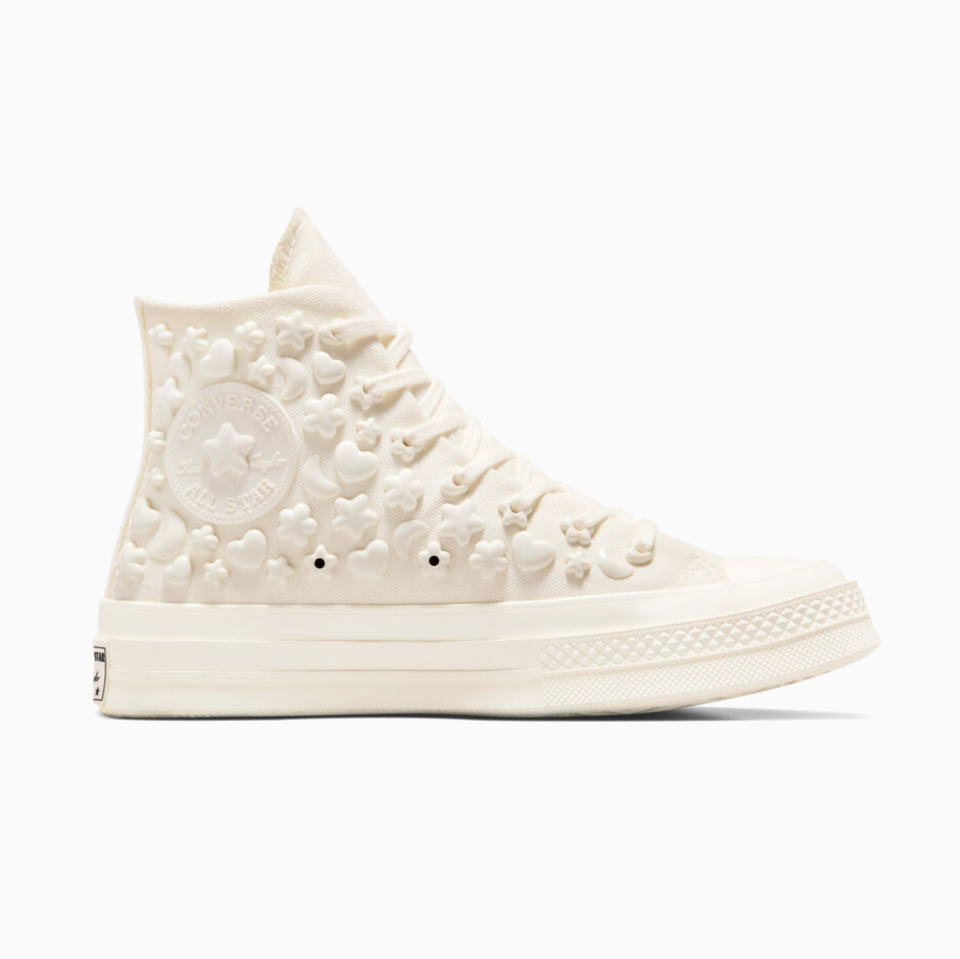 A white Converse high-top sneaker covered in white 3D charms