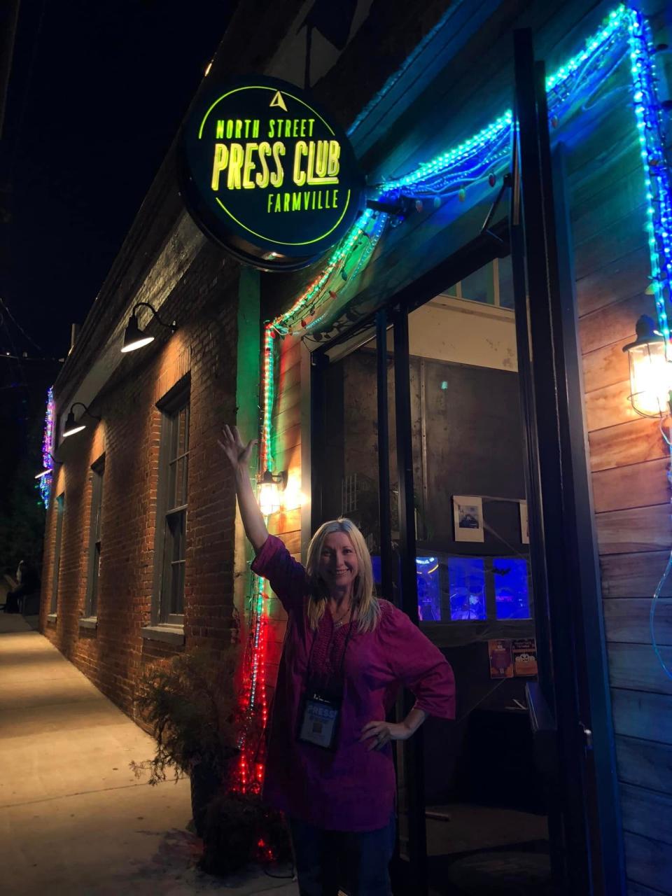 Columnist Kristi K. Higgins poses underneath the North Street Press Club neon sign in Farmville on October 28.
