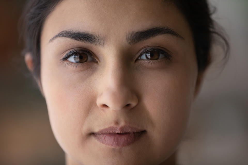 Face portrait of beautiful young woman. Close up of serious ethnic 20s 30s girl with perfect skin, well shaped black eyebrows, natural makeup looking at camera. Beauty care, ethnicity concept