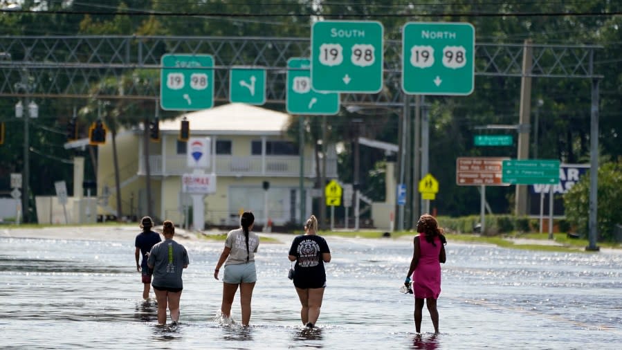 People walk through flood waters on SR44 Wednesday, Aug. 30, 2023, in Crystal River, Fla. Hurricane Idalia made landfall earlier this morning along the Big Bend of the state. (AP Photo/Chris O’Meara)