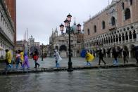 FILE PHOTO: People walk on a catwalk in the flooded St. Mark's Square in Venice, Italy