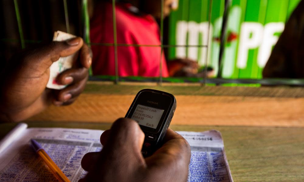 An employee uses a mobile phone inside an M-Pesa store in Nairobi