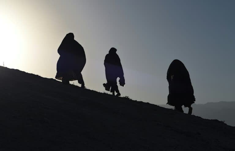 Afghan Shiite mourners ascend a hilltop to offer prayers for their relatives, members of the 'Enlightenment Movement', buried at a graveyard on the outskirts of Kabul