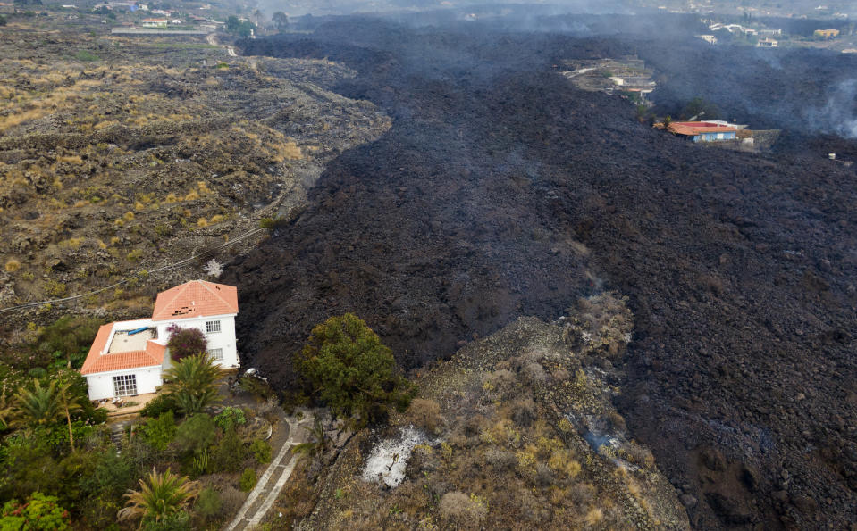 Lava from a volcano eruption flows destroying houses on the island of La Palma in the Canaries, Spain, Tuesday, Sept. 21, 2021. A dormant volcano on a small Spanish island in the Atlantic Ocean erupted on Sunday, forcing the evacuation of thousands of people. Huge plumes of black-and-white smoke shot out from a volcanic ridge where scientists had been monitoring the accumulation of molten lava below the surface. (AP Photo/Emilio Morenatti)