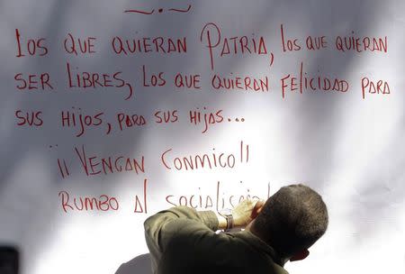 Late Venezuelan President Hugo Chavez writes a message after signing his support for a proposal to change the constitution, in Caracas in this December 11, 2008 file photo. REUTERS/Jorge Silva/Files