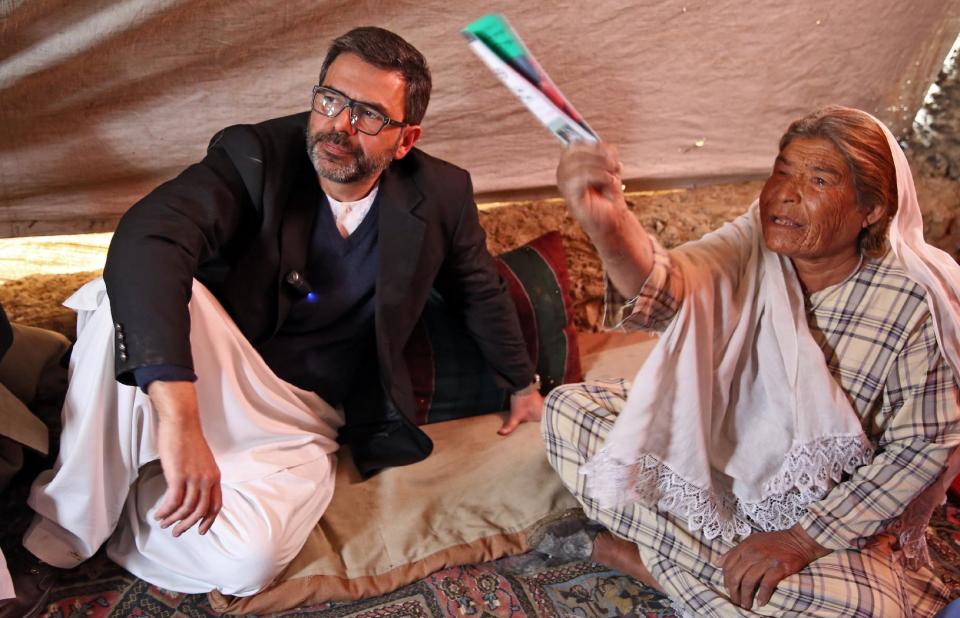 In this photo taken on Sunday, Feb. 23, 2014, former Afghan presidential candidate Mohammad Nadir Naim, left, listens to an Afghan internally displaced woman while campaigning in a poor neighborhood in Kabul, Afghanistan. (AP Photo/Massoud Hossaini)