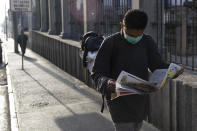 A man wearing a protective mask reads newspaper in Guatemala City, Tuesday, March 17, 2020. Guatemalan President Alejandro Giammattei effectively closed off Guatemala late Monday to all non-Guatemalans or permanent residents and ordered a suspension of all non-essential activities. For most people, the new coronavirus causes only mild or moderate symptoms. For some it can cause more severe illness. (AP Photo/Moises Castillo)
