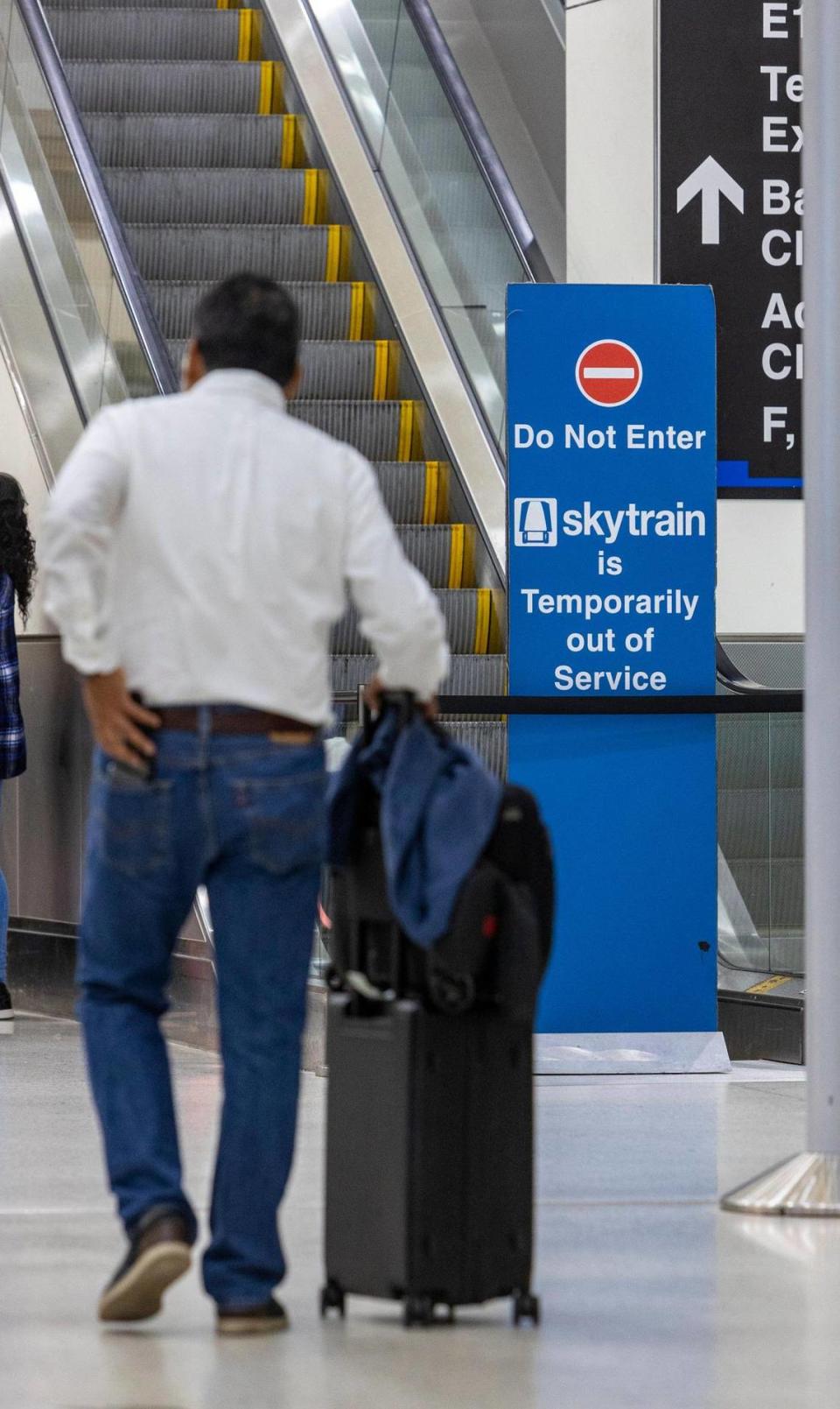 A man with his luggage walks past a closed entrance to the Skytrain on Concourse D at Miami International Airport. The Skytrain is down indefinitely and the courtesy shuttle is the only option passengers have besides walking to get from one end of the terminal to the other, Wednesday, Sept. 27, 2023.