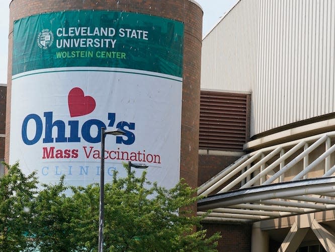 A man walks by signs for Ohio's COVID-19 mass vaccination clinic at Cleveland State University, Tuesday, May 25, 2021, in Cleveland.