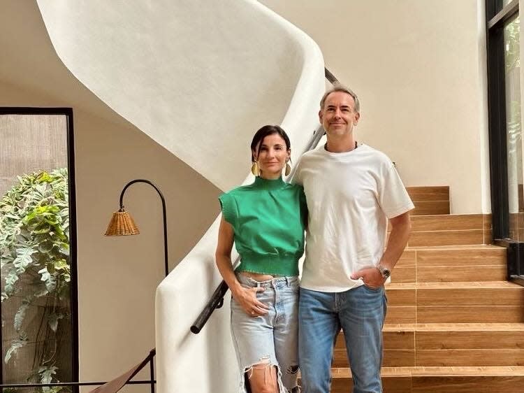 A man and a woman standing along the steps of a curved staircase.