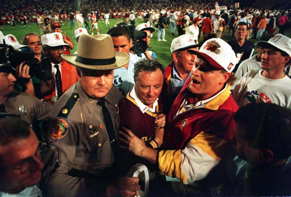 FLORIDA STATE SEMINOLES HEAD COACH COACH BOBBY BOWDEN IS ESCORTED OFF THE FIELD AFTER HIS TEAM DEFEATED NEBRASKA, 18-16 IN THE 1994 ORANGE BOWL IN MIAMI, FLORIDA.