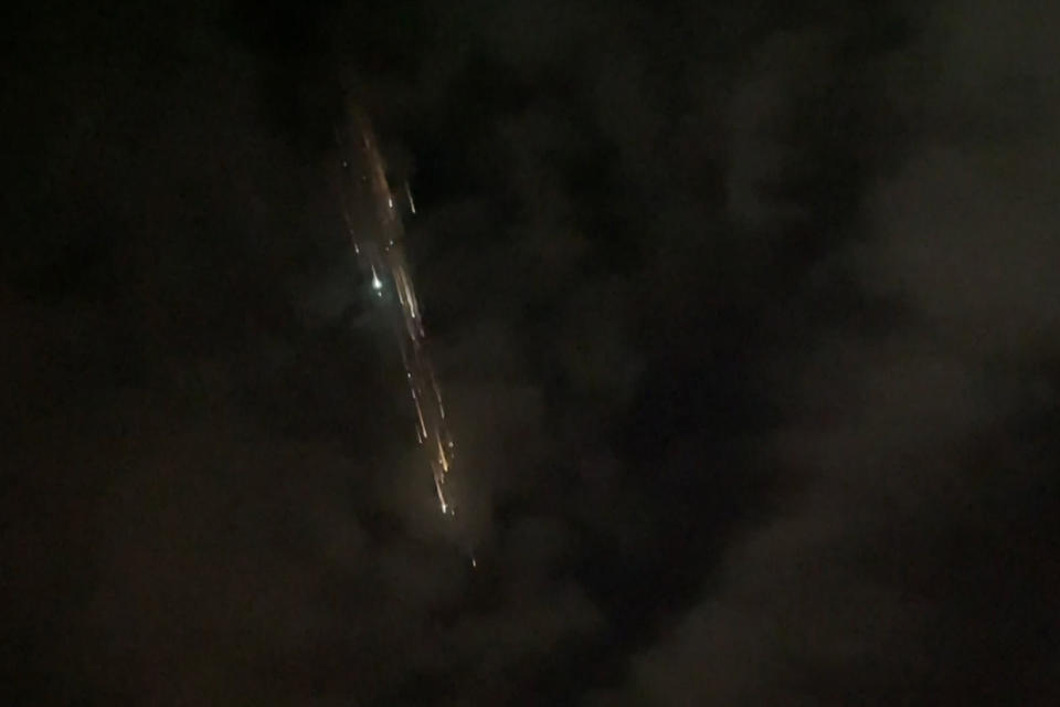 In this image taken from video provided by Roman Puzhlyakov, debris from a SpaceX rocket lights up the sky behind clouds over Vancouver, Wash. Thursday evening, March 25, 2021. The remnants of the second stage of the Falcon 9 rocket left comet-like trails as they burned up upon re-entry in the Earth's atmosphere according to a tweet from the National Weather Service. (Roman Puzhlyakov via AP)