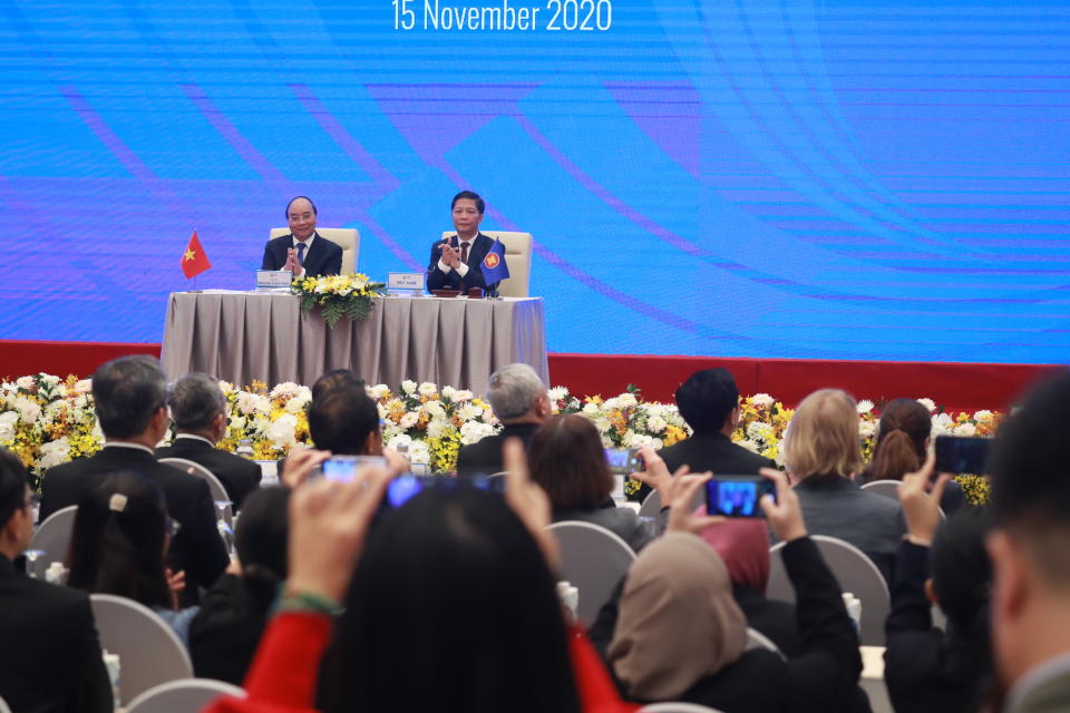 Vietnamese Prime Minister Nguyen Xuan Phuc, left, and Minister of Trade Tran Tuan Anh, right, attend the signing ceremony of The Regional Comprehensive Economic Partnership, or RCEP, trade agreement in Hanoi, Vietnam on Sunday, Nov. 15, 2020. China and 14 other countries have agreed to set up the world's largest trading bloc, encompassing nearly a third of all economic activity, in a deal many in Asia are hoping will help hasten a recovery from the shocks of the pandemic. (AP Photo/Hau Dinh)