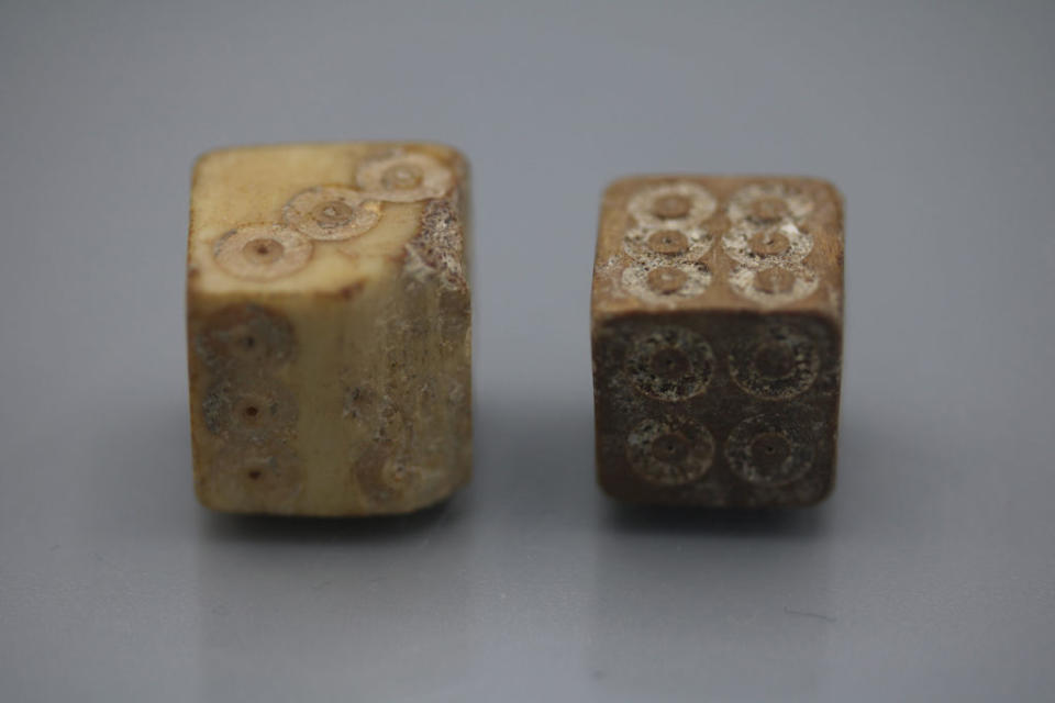 Two antique dice with worn surfaces on a plain background