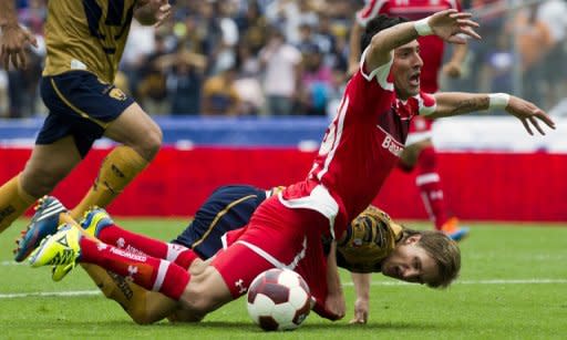 Antonio Garcia (atrás) de Pumas y Edgar Benitez, del Toluca, caen al suelo durante un partido por la Liga mexicana disputado el 12 de agosto de 2012 en Ciudad de México. Toluca venció 2-1 a los Pumas. (AFP | omar torres)