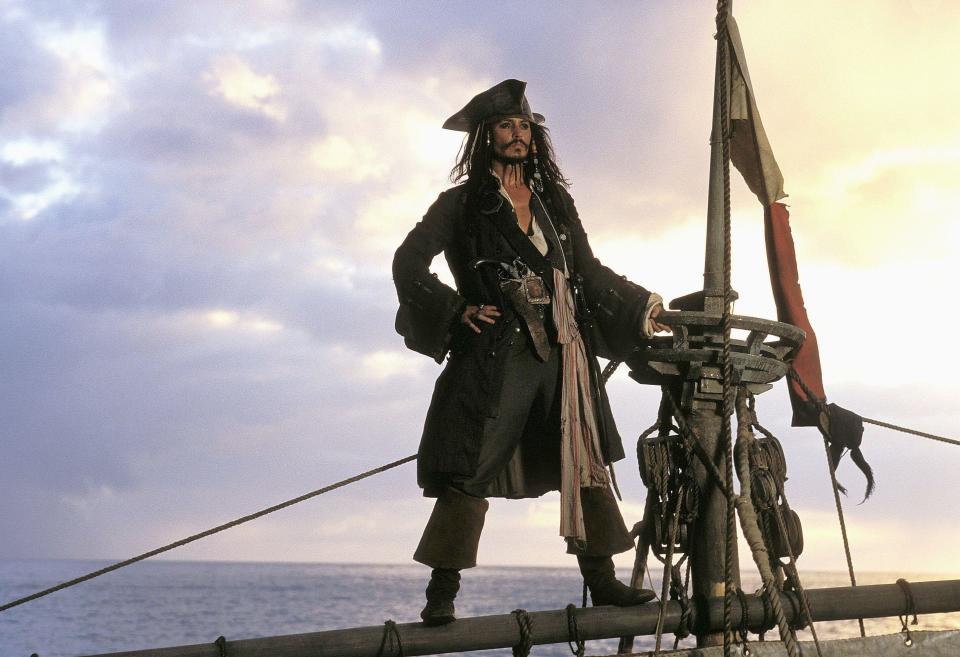 Johnny Depp standing on a ship looking at the ocean in Pirates of the Caribbean: The Curse of the Black