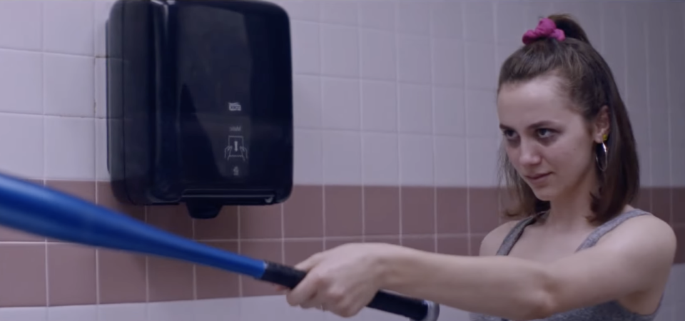 Maude Apatow pointing a baseball bat toward someone