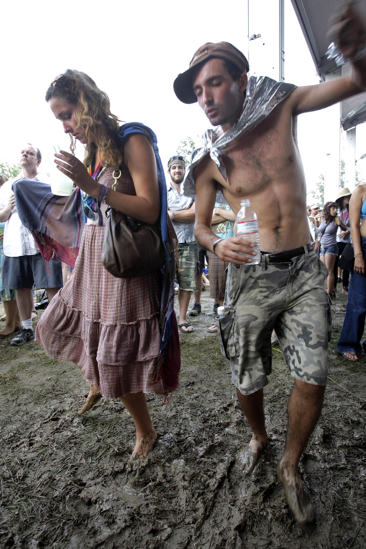 FILE - Georgia Ainsworth, left, of Toronto, and Lee Piazza, right, of Ottawa, dance in the mud during a concert by Iron and Wine at the Bonnaroo music and arts festival in Manchester, Tenn., June 14, 2008. Heavy rains from Hurricane Ida have forced Bonnaroo to cancel as organizer say the waterlogged festival grounds are unsafe for driving or camping. On social media, the festival said on Tuesday, Aug. 31, 2021, that tremendous rainfall over the last 24 hours, remnants of Ida’s powerful winds and rain, have saturated the paths and camping areas. (AP Photo/Mark Humphrey,File)