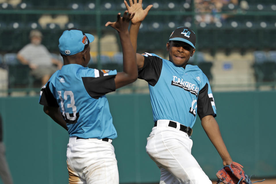 Curacao's Jurdrick Profar (13) and Curley Martha (12) celebrate the 9-2 win over Venezuela during a baseball game at the Little League World Series tournament in South Williamsport, Pa., Tuesday, Aug. 20, 2019. (AP Photo/Tom E. Puskar)