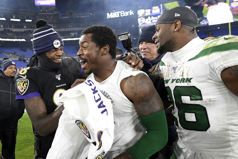 Baltimore Ravens quarterback Lamar Jackson, left, laughs with New York Jets outside linebacker James Burgess, center, as running back Le'Veon Bell, right, looks on after an NFL football game, Thursday, Dec. 12, 2019, in Baltimore. The Ravens won 42-21. (AP Photo/Nick Wass)