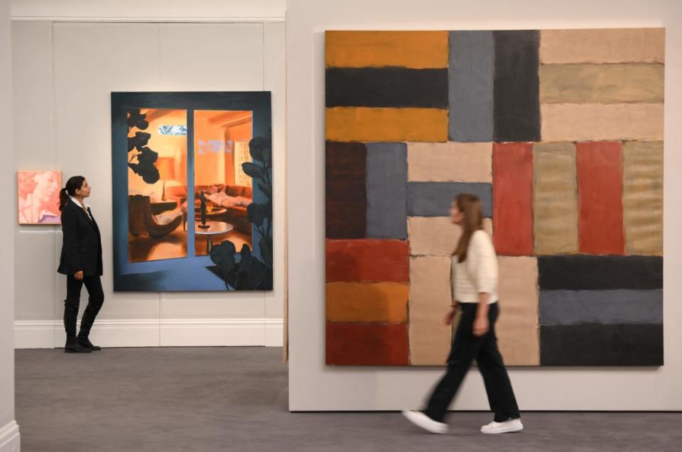 <div class="inline-image__caption"><p>A member of staff poses with a painting titled <em>Wall of Light Red</em> by Sean Scully and a painting titled <em>Indoor</em> <em>Outdoor</em> by Caroline Walker during a press view for "Frieze Week Sales of Contemporary Art" at Sotheby's, London, on Oct. 7, 2022.</p></div> <div class="inline-image__credit">Daniel Leal/AFP/Getty</div>