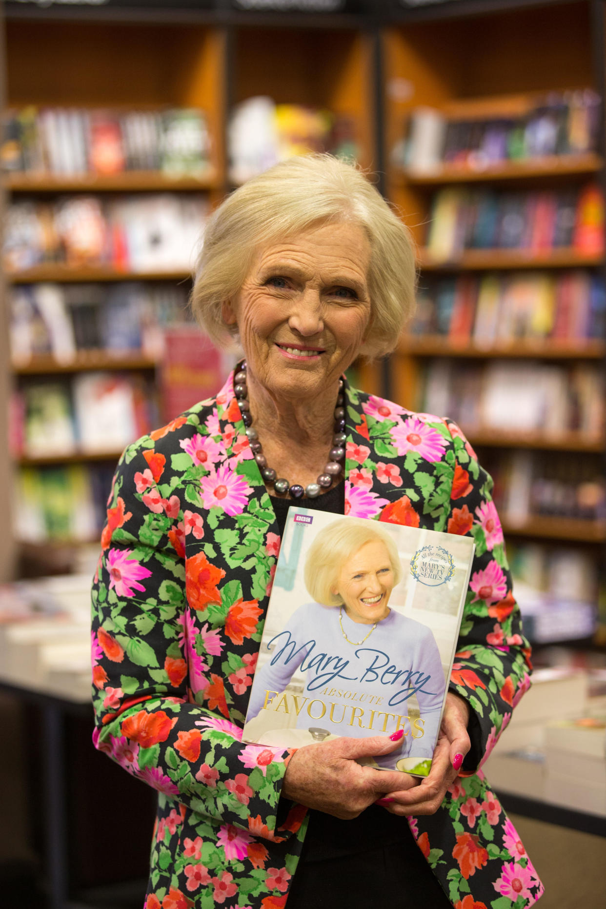 MAry Berry poses in floral jacket with cook book