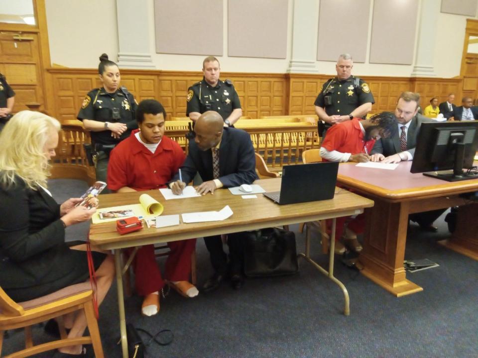 Criminal defendants Braylen J. Smallwood, at left, and Trezjon R. Allen, at right, sign court documents at their sentencing on Tuesday, when both were ordered to spend 20 to 25.5 years in prison for shooting at police detectives and other crimes.