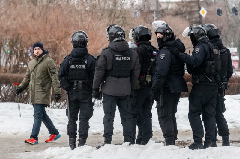 Police watch people as they lay flowers at a monument dedicated to victims of political repression to honor the memory of Russian opposition leader Alexei Navalny a day after news of his death. Andrei Bok/SOPA Images via ZUMA Press Wire/dpa