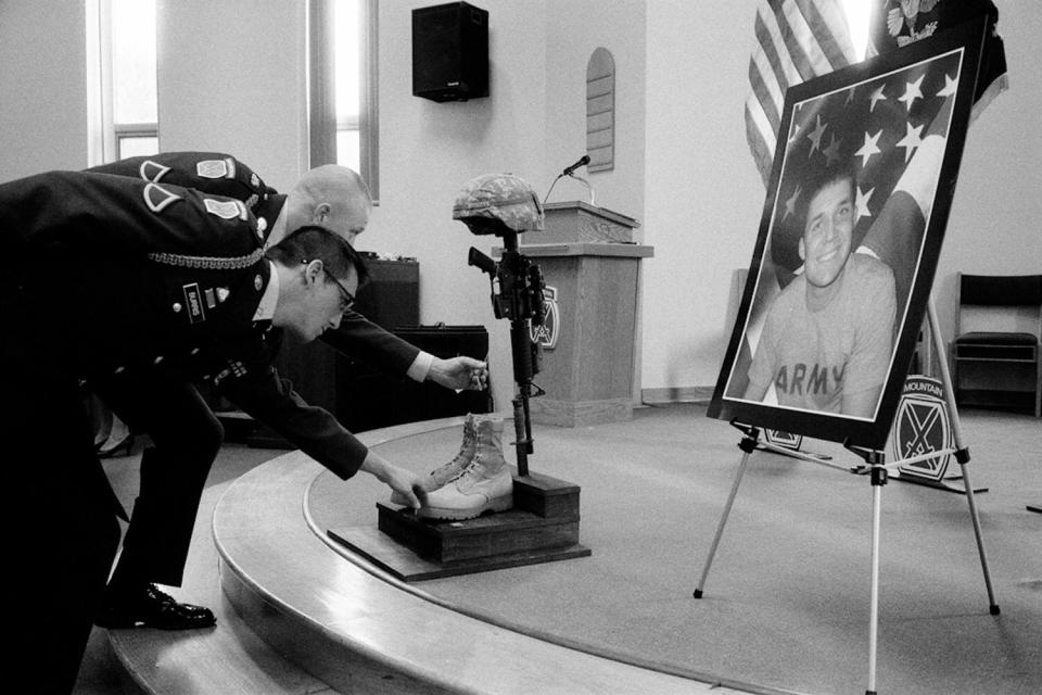 Two soldiers touch the dog tags of Staff Sergeant Cody Anderson at his memorial at Fort Drum, N.Y. January 2010.