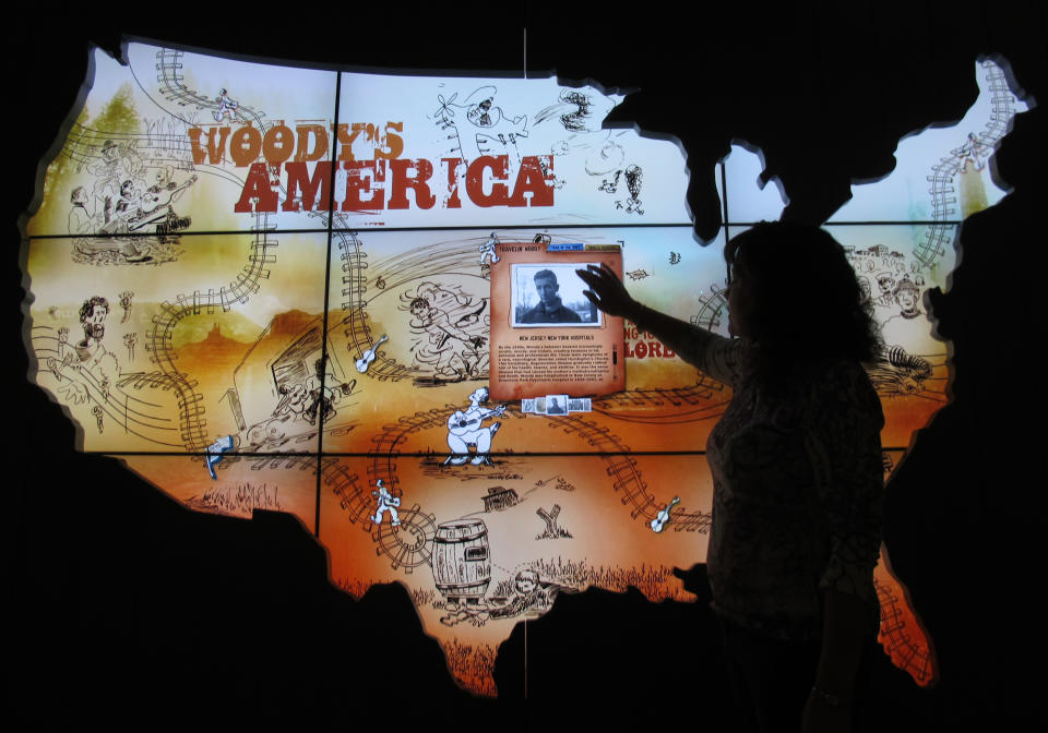 In this April 25, 2013, photo Deana McCloud, of the Woody Guthrie Center, tries out the Woody’s America interactive map at the Woody Guthrie Center in Tulsa. The 12,000 square-foot center, which opens to the public on Saturday, features many interactive exhibits chronicling the life and work of Woody Guthrie and is home to the folk singer’s archives. (AP Photo/Justin Juozapavicius)