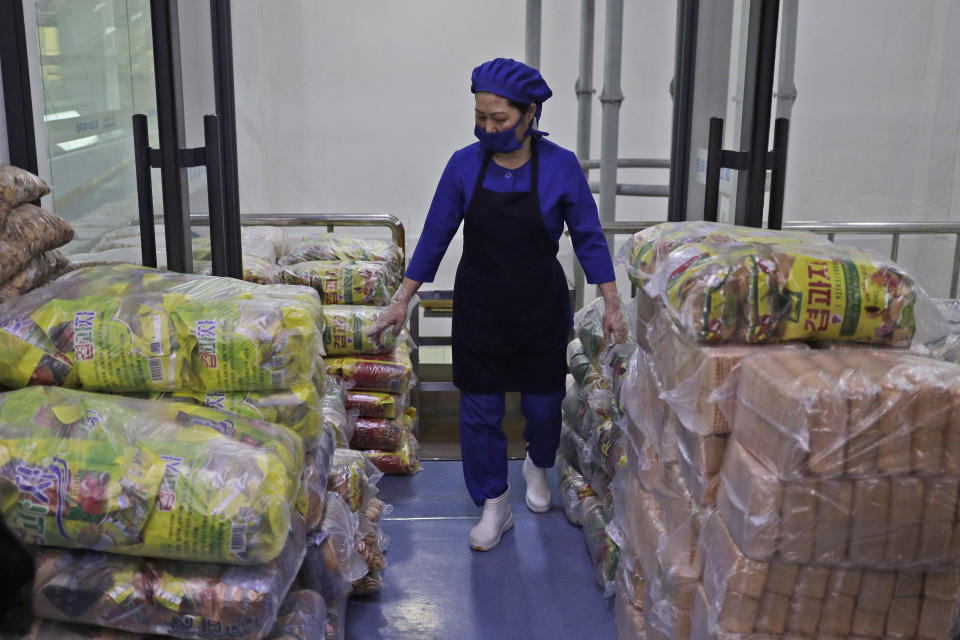 In this March 13, 2019, photo, a worker walks among stacks of food at Kumkhop Trading Co. food factory in Pyongyang, North Korea. North Korean factories are filling city store shelves with ever better and fancier snack foods and sugary drinks, while government officials and international aid organizations warn the nation could be on the verge of a major food crisis. (AP Photo/Dita Alangkara)