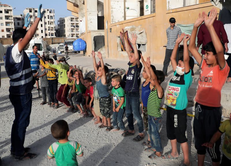 A volunteer entertains internally displaced children, amid concerns over the spread of the coronavirus disease (COVID-19), at an IDP camp in Idlib