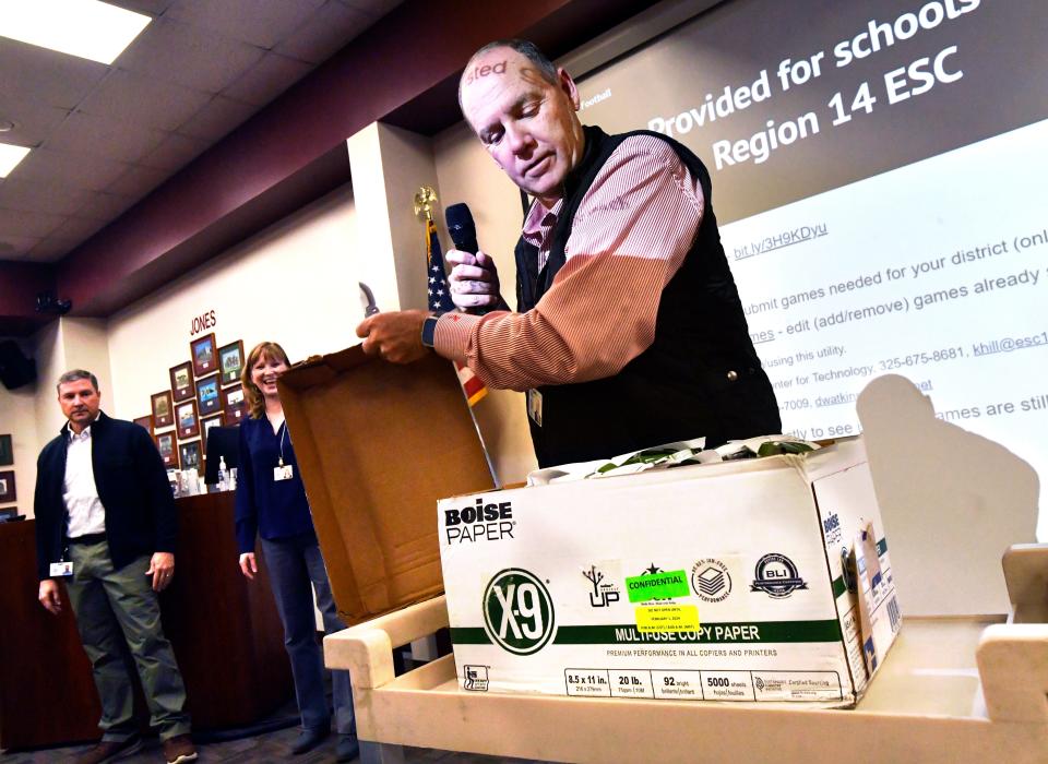 Shane Fields, the Executive Director of Region 14 Education Service Center in Abilene, opens the box containing the new UIL Realignment reports for a room of regional coaches Thursday.