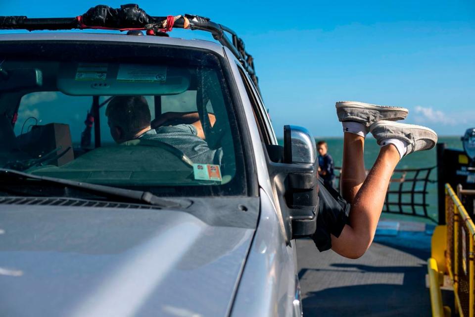 Patrick Hardesty, age 14, of Gilette, Wymoning, dives into the truck cab to grab some candy aboard the Cape Point Ferry from Hatteras to Ocracoke on Thursday, July 1, 2021.