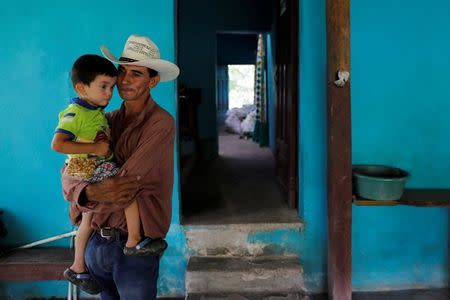FILE PHOTO: Jose Guardado, 42, a deportee from the U.S. and separated from his son Nixon Guardado, 12 at the McAllen entry point under the Trump administration's hardline immigration policy, carries his youngest son Neimar, 3, as he arrives at his home in Eden, Lepaera, Honduras June 23, 2018. REUTERS/Carlos Jasso