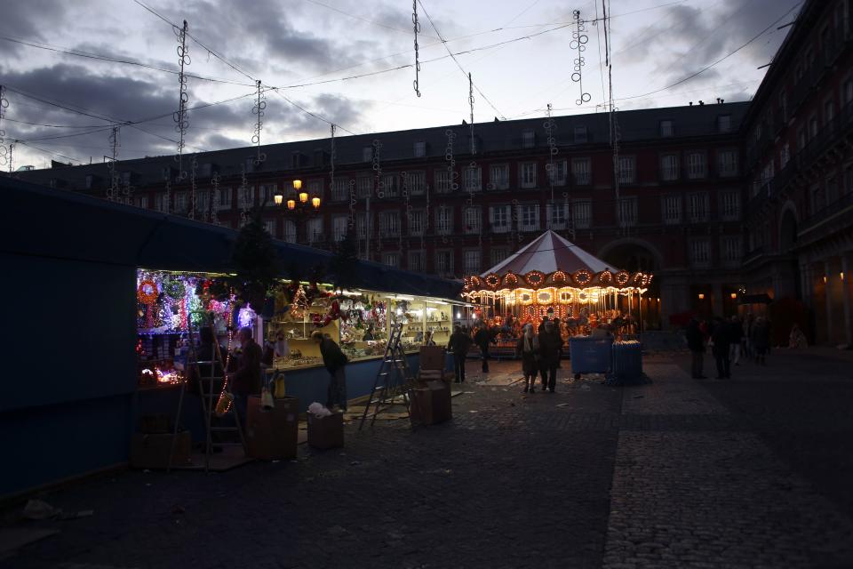 People walk past vendors setting up a Christmas market at Madrid's Mayor square